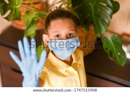 young woman holding blank sign. Coronavirus. Woman with face mask on quarantine, cooks in the kitchen at home during coronavirus crisis. Stay at home. Enjoy cooking at home. Family concept.