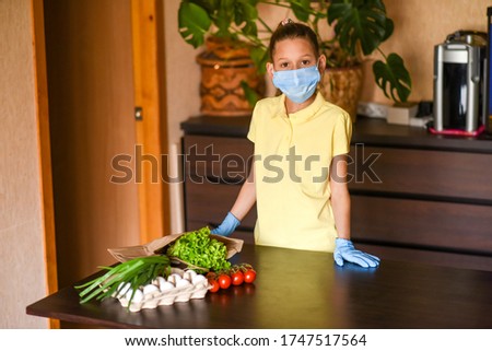 young woman holding blank sign. Coronavirus. Woman with face mask on quarantine, cooks in the kitchen at home during coronavirus crisis. Stay at home. Enjoy cooking at home. Family concept.