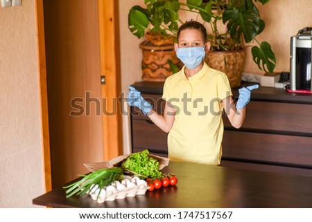 young woman holding blank sign. Coronavirus. Woman with face mask on quarantine, cooks in the kitchen at home during coronavirus crisis. Stay at home. Enjoy cooking at home. Family concept.