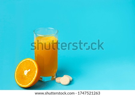 
tablet of vitamins with the taste of orange is dissolved in a glass of water on a blue background.     Сoncept of natural and chemical vitamins. Copy space.