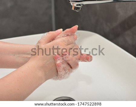 A young woman washes her hands according to the rules of hygiene during an epidemic period. Banner with quarantine, anti coronavirus and handwashing concept.