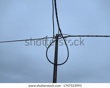 bundles of electronic wires on a metal pipe on a background of gray clouds