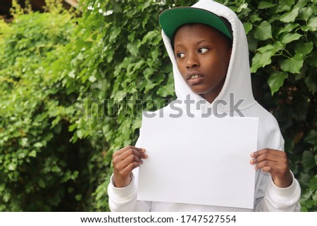 Black Child holding blank white paper sign looking to side 