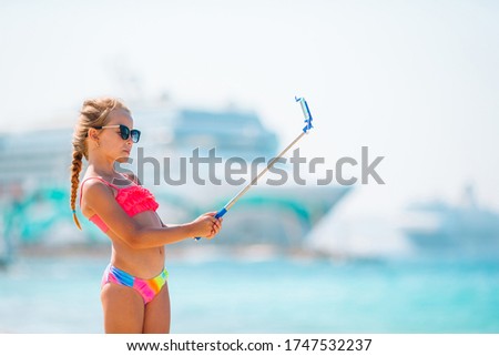 Little girl taking selfie portrait with her smartphone on the beach