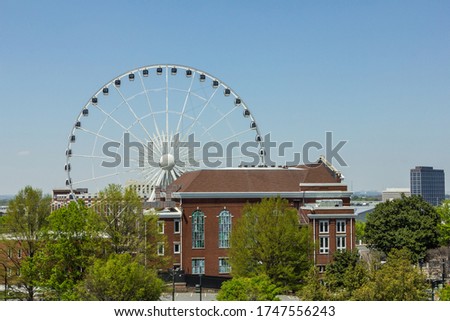 Giant white ferris wheel behind a vintage red brick building in urban Atlanta Georgia on clear blue day