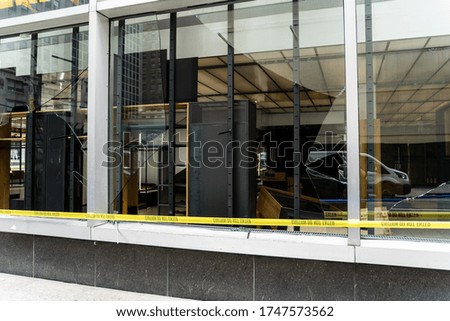 broken window with yellow strip "caution do not enter". damaged store inside