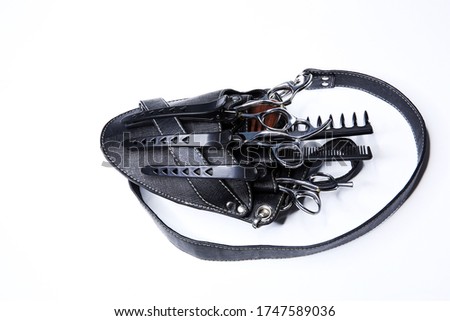 Holster for the hairdresser. Barber tool bag isolated on white background. Black bag with pockets, a plastic comb, metal scissors, black hairpins and combs Royalty-Free Stock Photo #1747589036