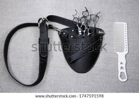 Holster for the hairdresser top view. Barber tool bag isolated on canvas. Black bag with pockets, a plastic comb, metal scissors, black hairpins and white combs Royalty-Free Stock Photo #1747591598