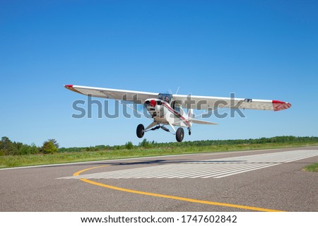 Small white single engine airplane takes off from a municipal airfield in rural Minnesota Royalty-Free Stock Photo #1747602842