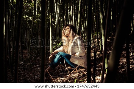 woman sitting between bamboo looking for rays of light