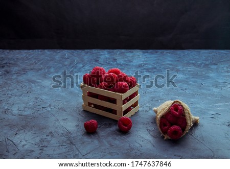 Red raspberries placed on a small wooden fence and jute bag.