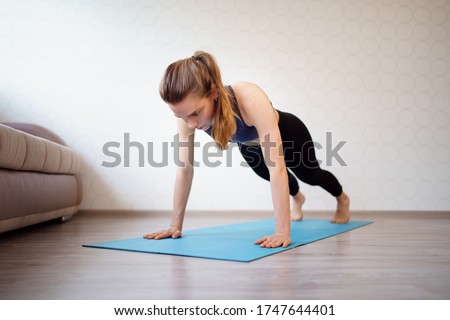 the girl is engaged in sports at home online workouts on the laptop. fitness exercise - pushups and plank