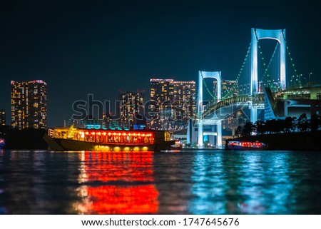 Japan. Evening in Tokyo. A pleasure ship sails through Tokyo Bay. Water evening walk on Tokyo Bay. Rainbow bridge in the evening. The island of Odaiba in the dark.