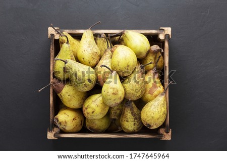 Ripe pears in  wooden crate  black concrete background. Harvest concept.