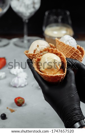 Hands in black protective gloves holds a waffle cone with ice cream. protection against coronovirus. Concept of selling ice cream during quarantine. Ice cream in hands in protective black gloves.