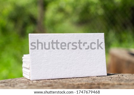 Blank letterpress business cards stack lying on a stump outdoor stage as template for design presentation, brand promotion, portfolio etc. Camping nature concept.