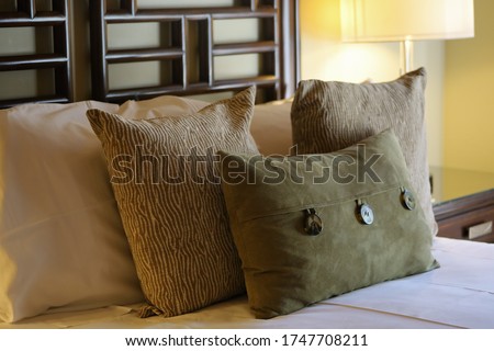 View of a bed with decorative pillows in earthy natural colors.