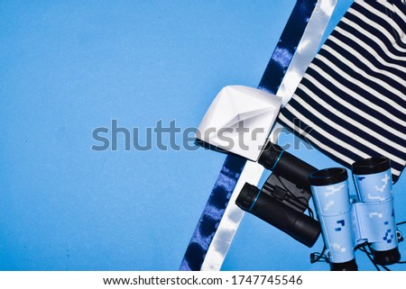 Sailor's Day. June 25th. The concept of a holiday, the sea. View from above. Vest, binoculars, paper boat on a blue background. place for text.
