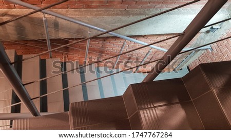 Red brick building with a modern staircase in a loft style with metal railing. Stairs adorn the building. Modern stairwell. Steel railing. Staircase in perspective.