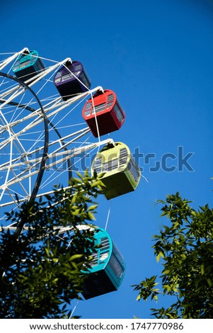 multi-colored cabins of a ferris wheel in an amusement park on a background of blue sky