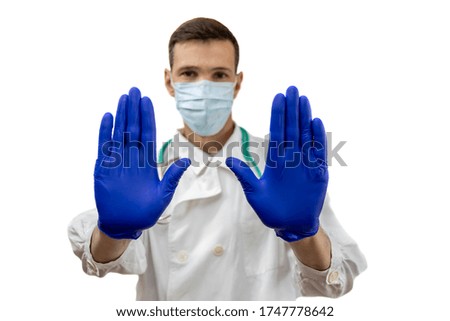 Young doctor with stethoscope in  protective mask and gloves with open hands doing stop sign isolated on white background, defense gesture. Focus on hand.