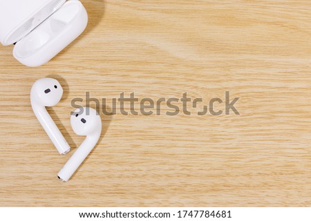 Top view of White Earphones wireless with Battery charger on wood texture background. Copy space.