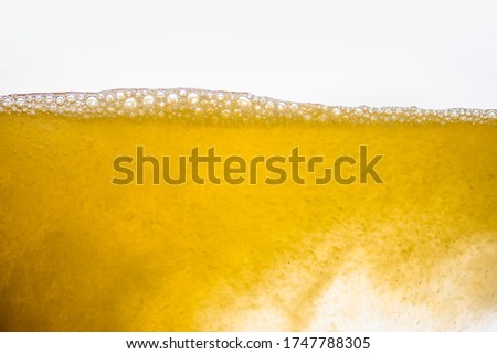 Background of close-up soda bubbles mixed with yellow fruit juice on white background.