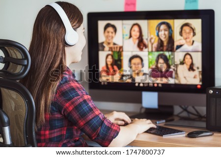 Rear view of Asian woman working and online meeting via video conference with colleague and team building when Covid-19 pandemic,Coronavirus outbreak,education and Social distancing,new normal concept Royalty-Free Stock Photo #1747800737