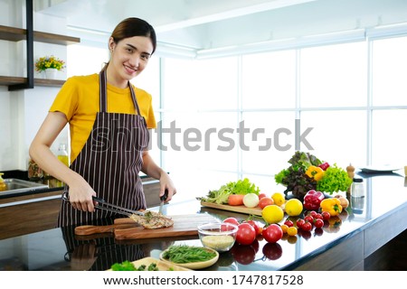 Asian women present fresh food. Housewife trying to cooking and showing pork of steak in kitchen in house to take picture for sell food box online. Work from home / Stay at home / covid19 concept 