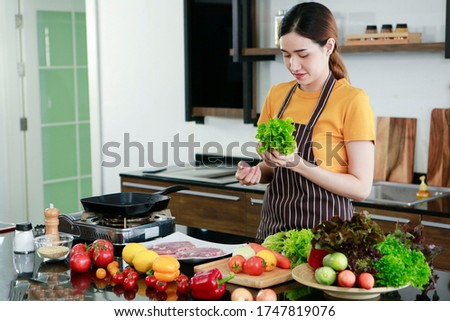 Asian women present fresh food. Shot housewife trying to cooking and showing vegetable in kitchen in house to take picture for sell food box online. Work from home / Stay at home / covid19 concept 