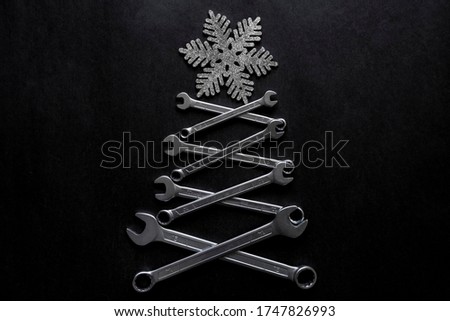 Abstract christmas tree made of wrenches with snowflate on the top on black background. Industrial christmas, winter, new year concept. Home decoration. Mechanic, handyman greeting card concept.