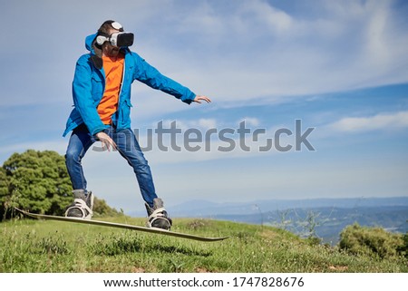 young man wearing virtual reality glasses thinks he is snowboarding