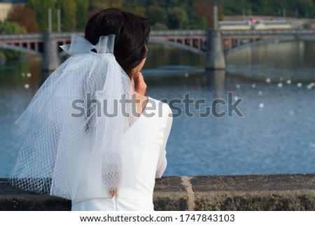 The bride admires Prague from Charles Bridge. Girl in a wedding dress with a veil.