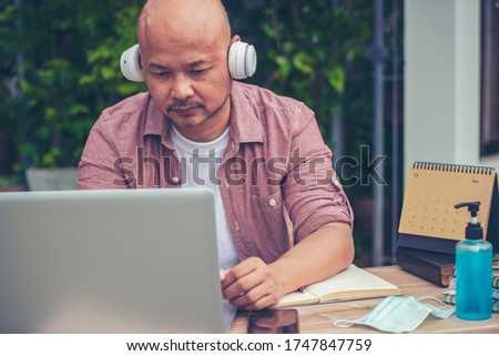 Businessman working online at the home office by laptop. Asian senior entrepreneurs watching webinars and talking during meeting video conferences calls with team, and using mobile phone. 
