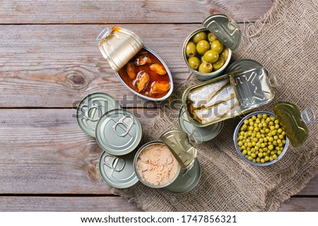 Assortment of different canned preserved vegetables, meat, fish, seafood in tin cans on a wooden table. Non-Perishable goods, food, donations concept. Flat lay top view background  Royalty-Free Stock Photo #1747856321