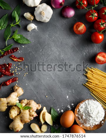 Empty black board and ingredients on dark background. Free space for text and brand product. Tomatoes, ginger, garlic, chilli, egg, flour and basil leaf. Top view