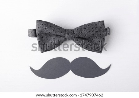Top view of grey bow tie ad mustache on the white surface.Concept of greeting card, happy fathers day