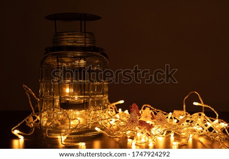A closeup shot of a jar on the table with Christmas lights and ornaments against a dark background