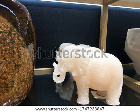 Decorative elephant-shaped candle and vase with an ombre effect on shelf in decor store. Decorations for living room interior. Ideas for a modern interior. Decor and tableware shop