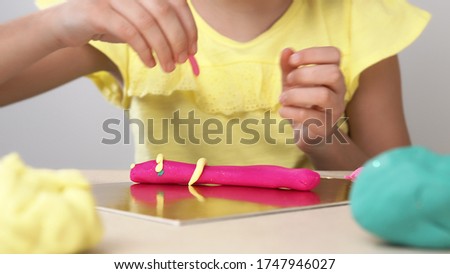 Children's hands close-up roll plasticine on the Board. Children's play with plasticine. Children's creativity and creativity.