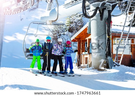 Group of children take off from ski chairlift on top of the mountain station together on alpine resort