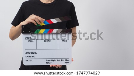 Hand is holding clapper board or movie slate and standing on white background. it is used in video production and film industry.