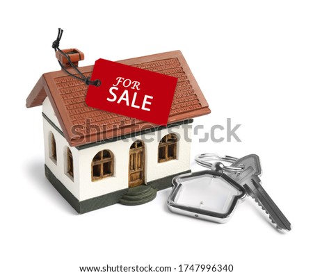Key and house model with SALE label on white background