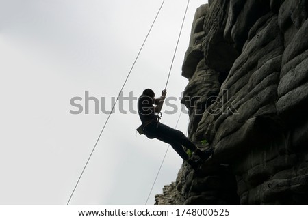 Silhouette of climber on a cliff over the  mountain. Extreme sports. man climbing challenging route going along rock