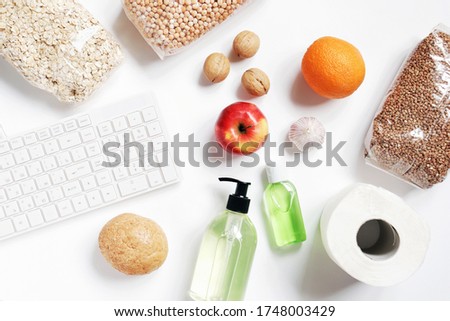 Online grocery shopping flat lay stock photo. Purchasing food and hygiene products during the coronavirus pandemic. Cereals, fruits, sanitizer hand washing gel and toilet paper