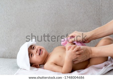 Asian parent's hand is wiping the body of his crying little baby boy to reduce the body temperature from the fever, concept of home remedies for child illness by parent. Royalty-Free Stock Photo #1748004686