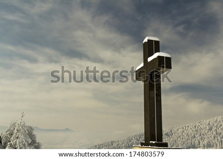 Cross covered in snow on a blue sky background