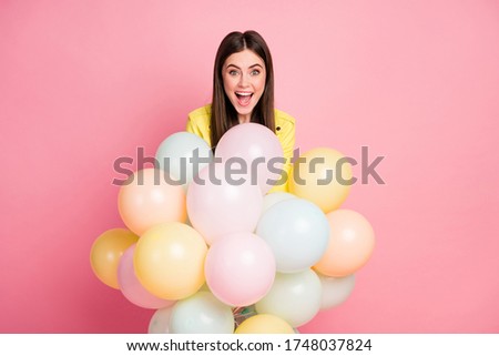 Photo of funny charming lady hold hands many air balloons festive event birthday party open mouth wear trend yellow leather jacket isolated pastel pink color background