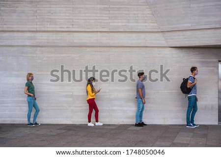 Group of young people waiting for going inside a shop market while keeping social distance in a line during coronavirus time - City outbreak lifestyle, protective face mask and spread virus prevention Royalty-Free Stock Photo #1748050046