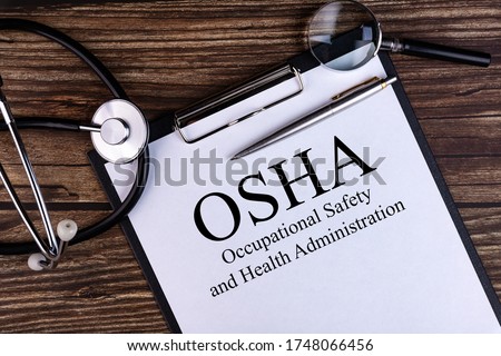 OSHA text written in a notebook lying on a desk and a stethoscope. Medical concept. Royalty-Free Stock Photo #1748066456